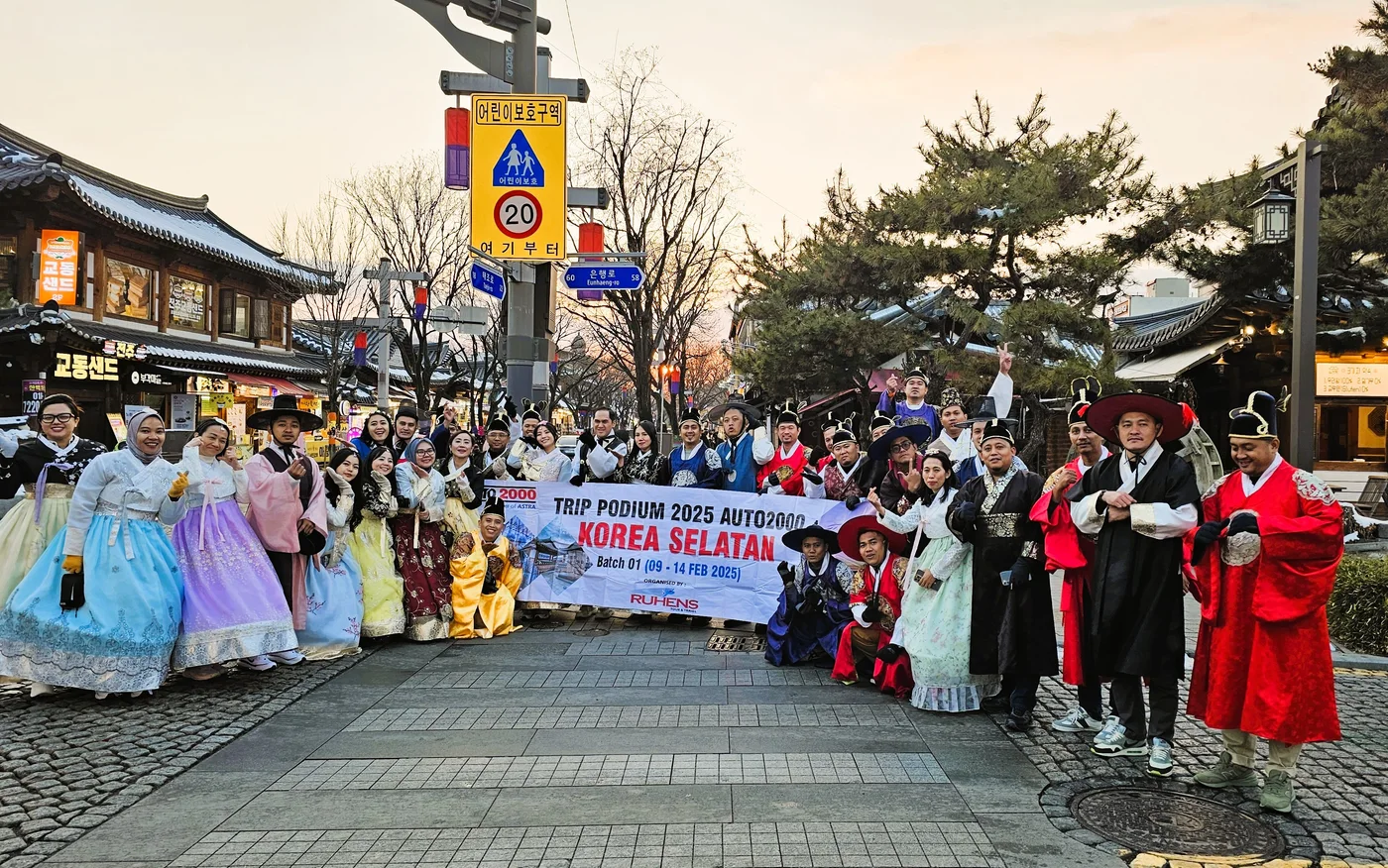Peserta perjalanan Ruhens mengenakan pakaian tradisional Korea dan berfoto bersama spanduk grup.