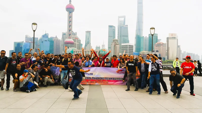 Grup perjalanan Ruhens berfoto dengan spanduk di depan cakrawala Shanghai.