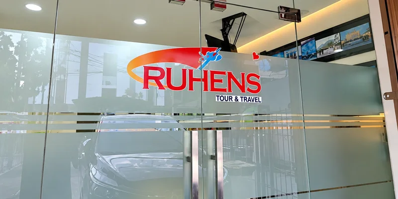 Pintu kaca dengan logo Ruhens Tour & Travel.
