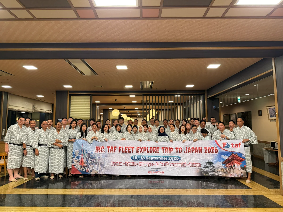 Grup perjalanan berfoto di dalam ruangan dengan spanduk TAF Fleet Explore Trip to Japan 2026.