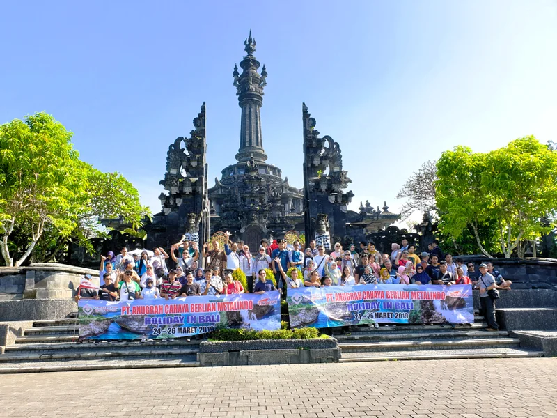 Grup perjalanan Ruhens dengan spanduk di depan monumen di Bali.